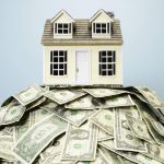 Model home resting on top of US paper currency