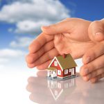 Hands and little house over sky background.