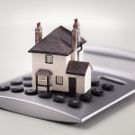 House resting on calculator concept for mortgage calculator, hom