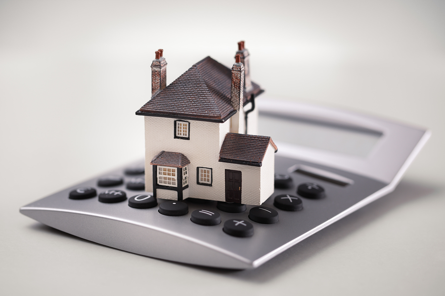 House resting on calculator concept for mortgage calculator, hom